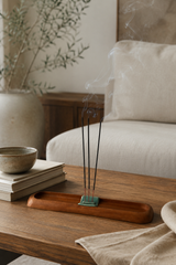 Incense sticks on a wooden tray with a bowl and books in the background