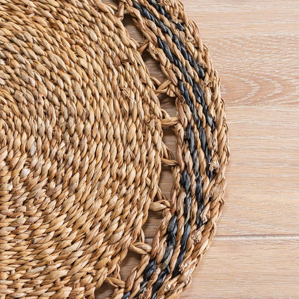 Woven placemats with a natural and black pattern on a wooden surface