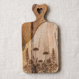Wooden cutting board with engraved designs on a table setting.