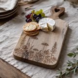 Wooden cutting board with engraved designs on a table setting.