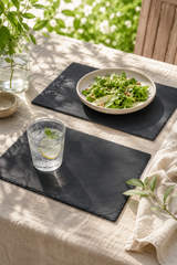 Table setting with a bowl of salad and a glass of water on Set of 2 rectangular slate placemats and serving platters made from natural slate with rustic edges.