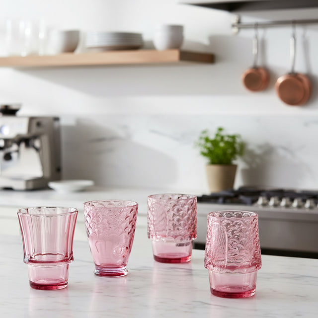 Set of four pink glass tumblers with textured design on a white background