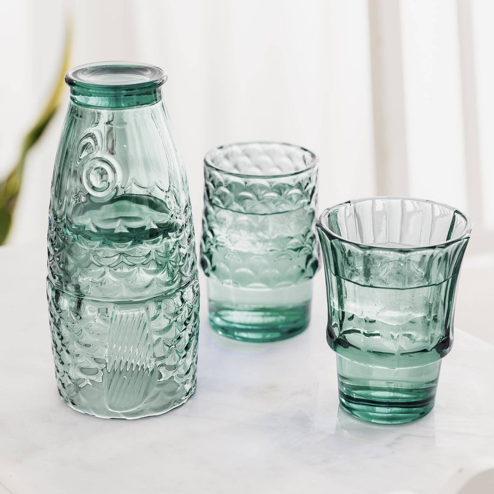 Set of green glass tumblers on a light background that make a fish when stacked together