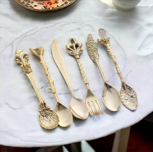 Set of ornate gold cutlery on a marble surface