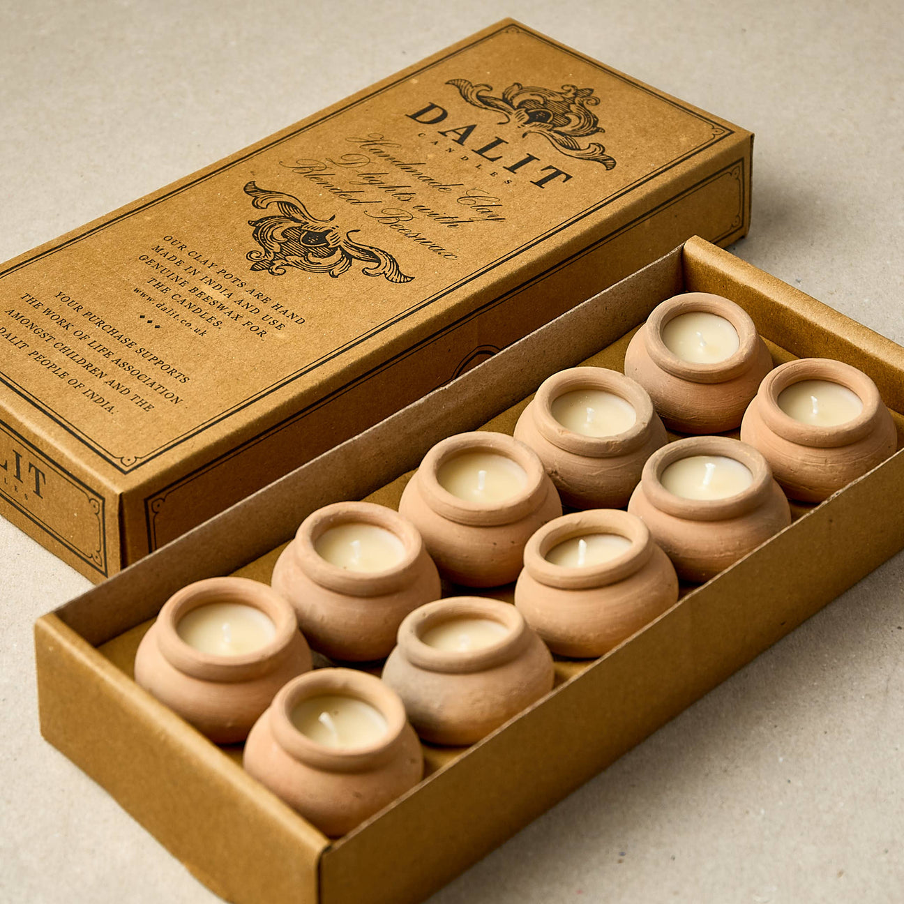 Set of small terracotta pots with candles inside, displayed in a brown box 