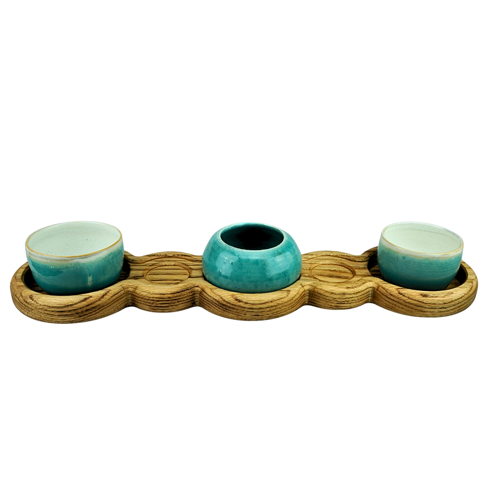 Three teal ceramic bowls on a wooden tray with a white background