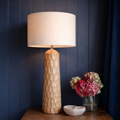 Table lamp with textured base on a wooden table against a dark blue wall