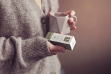 Person holding a mug and a box in a warm setting