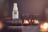 Spray bottle on books with candles in the background