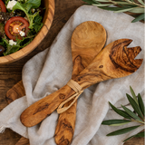 Set of wooden salad servers with olive design on a rustic background