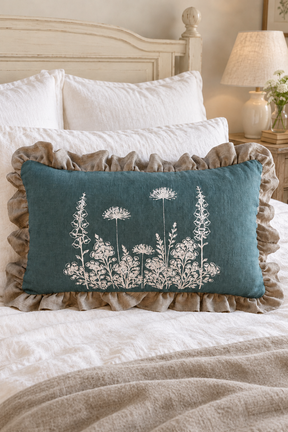 Duck egg Florilegium rectangular cushion on ivory bedding with a plain natural linen throw.