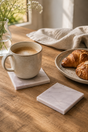 Cup of coffee on a marble coaster with croissants on a plate on a wooden table.