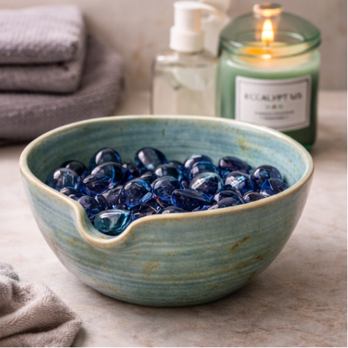 Stoneware bowl with decorative stones on a wooden surface.
