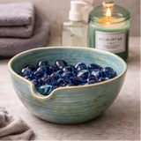 Stoneware bowl with decorative stones on a wooden surface.