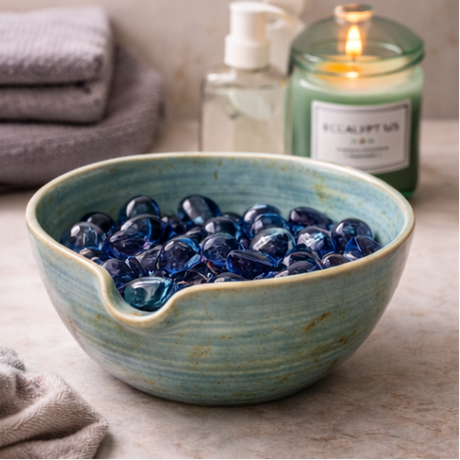 Stoneware bowl with decorative stones on a wooden surface.
