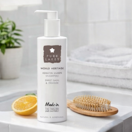 Pure Life Naturals products with a bottle, oranges, Sweet Basil & Orange Keratin Silken Shampoo.