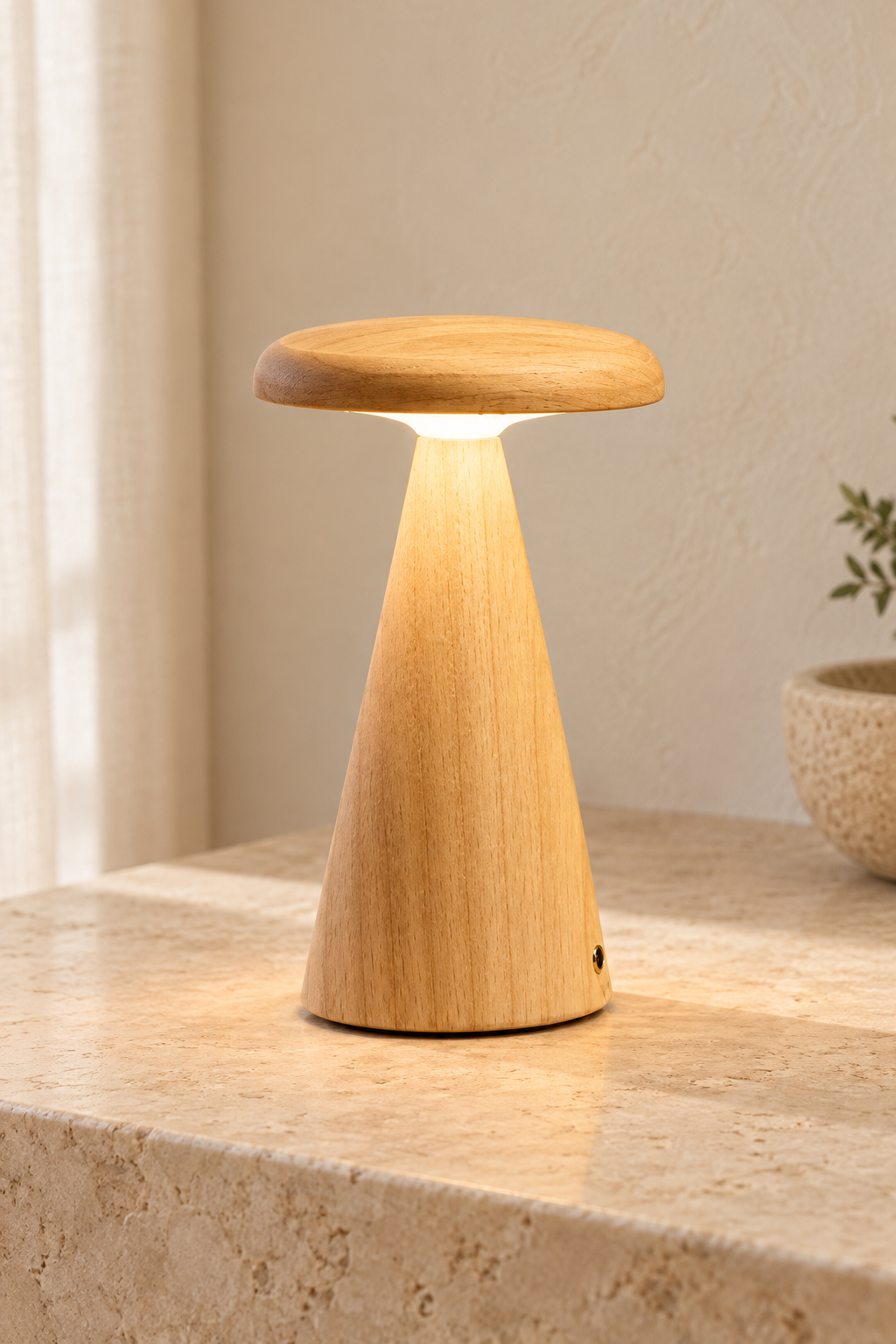 A mushroom-shaped wooden table lamp with a natural light wood finish, glowing with warm light from within, set on a stone surface in a softly lit interior.