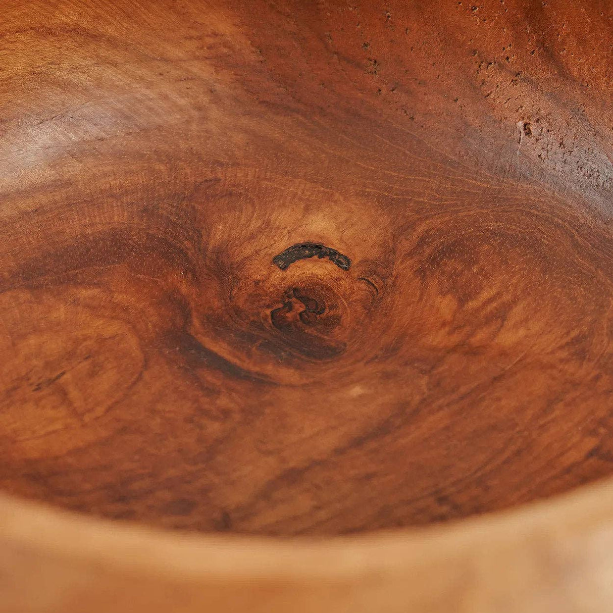 Close-up of the interior of a handcrafted Teak Root Fruit & Serving Bowl – 20cm wooden bowl, showcasing rich warm brown wood grain and a natural dark knot in the centre.