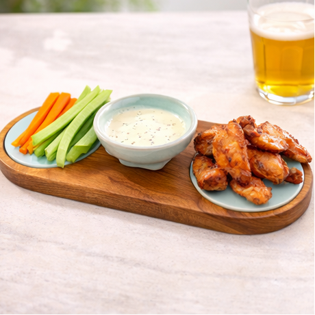 a wooden tray with snacks and dips on a table outdoors.