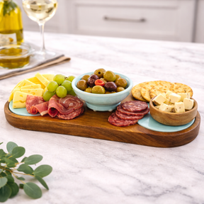 Wooden charcuterie board with assorted meats, cheeses, and fruits on a marble surface.