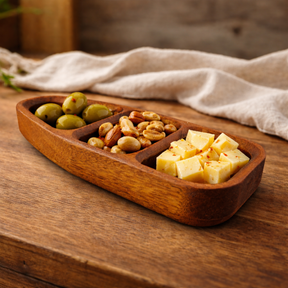 Wooden snack tray with olives, nuts, and cheese on a wooden surface.