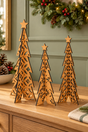 Three laser-cut wooden Christmas tree ornaments with star toppers, displayed on a wooden cabinet in a decorated holiday setting.