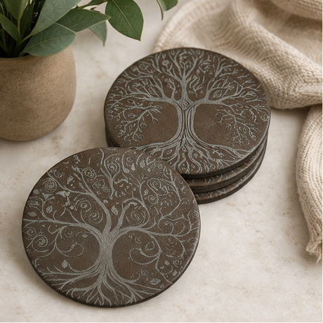Set of round Leather coasters with tree design on a light surface with a plant and fabric in the background.
