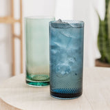 Two blue and green textured glass tumblers on a light surface with a blurred background