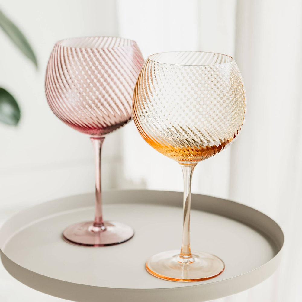 Two textured wine glasses on a white tray with a light background