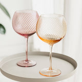 Two textured wine glasses on a white tray with a light background