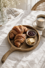 Walnut Wooden tray with croissants, jam, and butter on a light fabric surface.