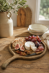Walnut  Wooden platter with assorted cheeses, fruits, and meats on a wooden table.