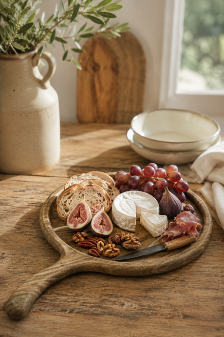 Walnut  Wooden platter with assorted cheeses, fruits, and meats on a wooden table.