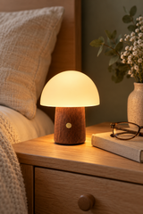 Mini Alice Mushroom Lamp in Walnut with its frosted shade glowing warm white