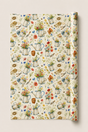A roll of wrapping paper with a vintage watercolor pattern of watering cans, flowers, and gardening tools on a cream background, shown partially unrolled.