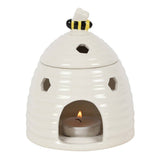 White ceramic beehive-shaped oil burner with a lit candle inside on a white background