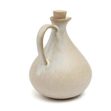 White ceramic oil bottle with cork stopper on a white background