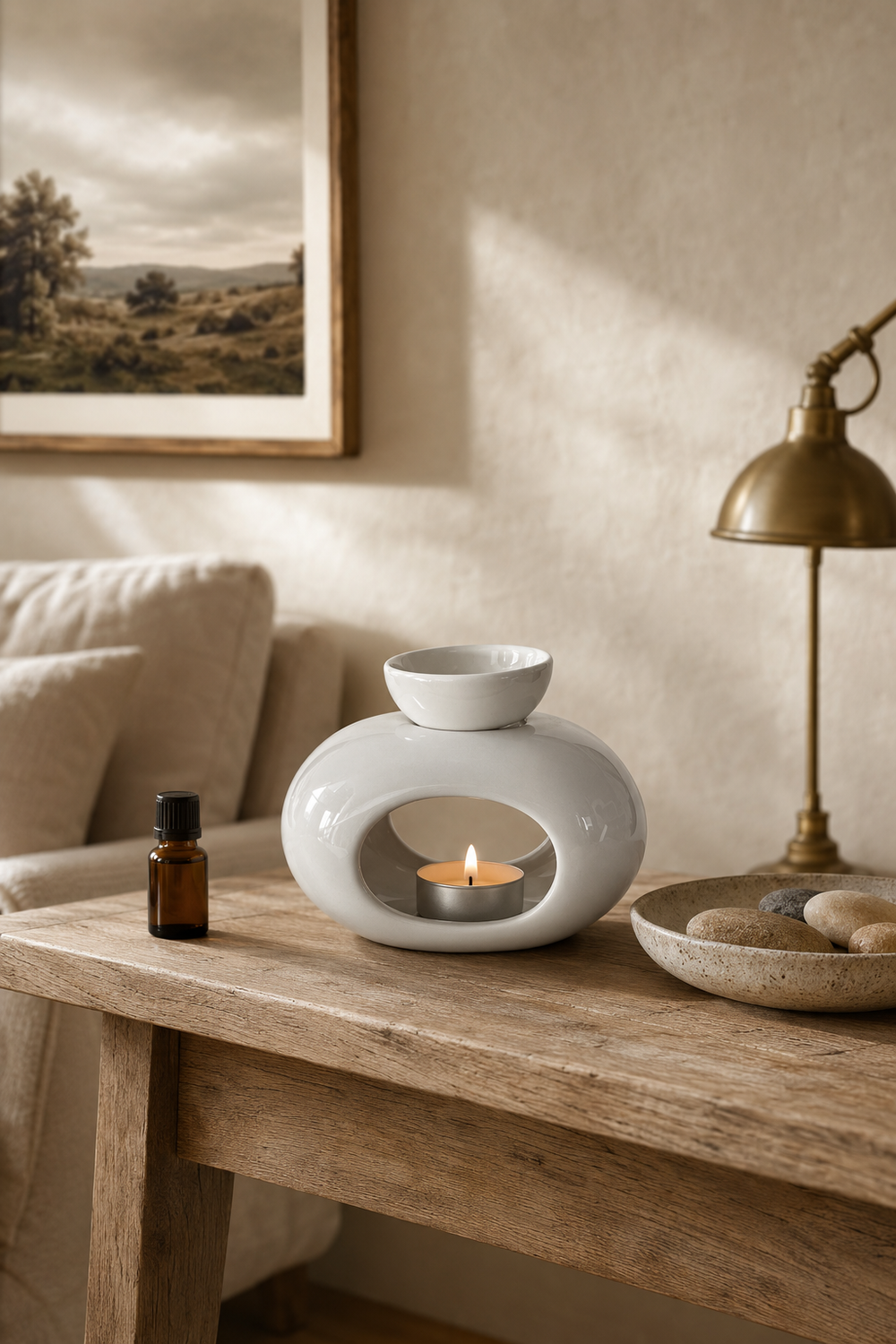 White oval oil burner with a lit tealight on an oak console table in a softly furnished neutral living room.