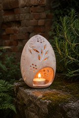 Whitewashed terracotta egg tealight lantern with hand-cut botanical leaves and small flower-shaped openings.