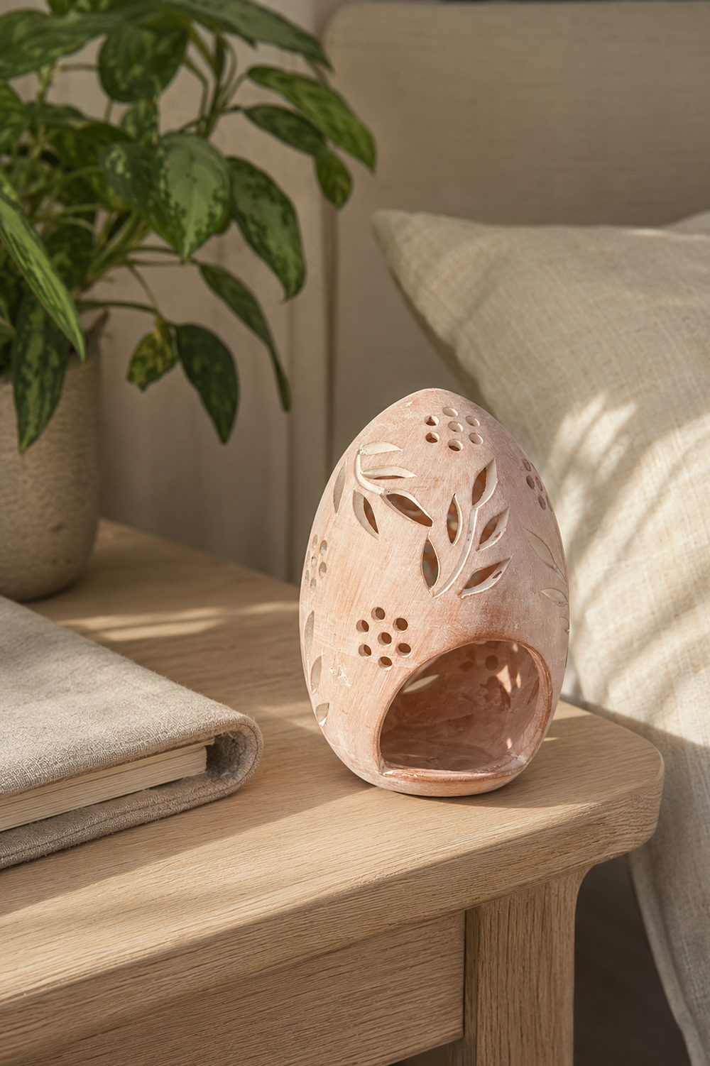 Whitewashed terracotta egg tealight lantern with hand-cut botanical leaves and small flower-shaped openings.