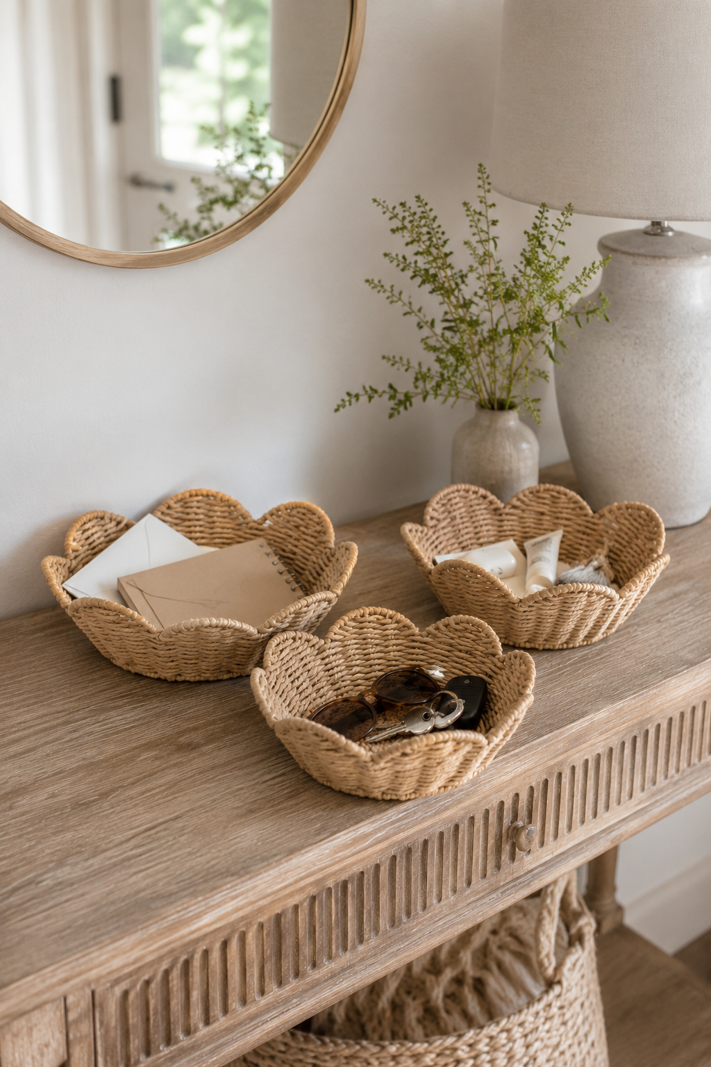 Wicker baskets on a wooden console table with a vase and plant in the background.