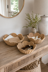 Wicker baskets on a wooden console table with a vase and plant in the background.