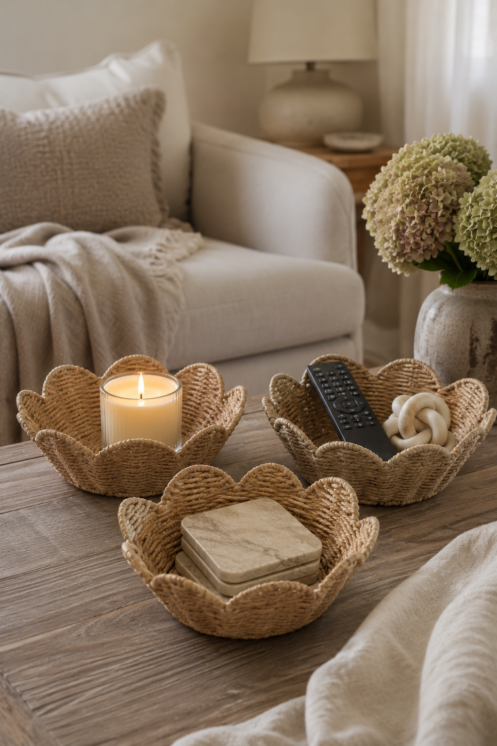 Woven baskets on a wooden table with a candle, remote control, and coasters in a cozy living room setting.