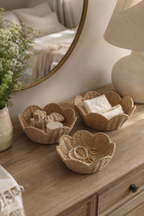 Three woven bowls on a wooden surface with a mirror and lamp in the background.