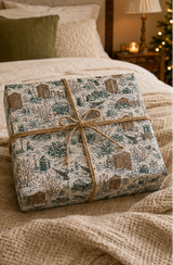 Winter allotment Christmas wrapping paper showing snow-covered sheds, fences, cold frames, cabbages, wheelbarrows, garden tools and robins in deep green and brown.