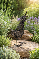 Decorative bird sculpture on a rock surrounded by garden plants