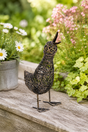Decorative bird sculpture on a wooden surface with flowers in the background