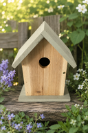 Wooden birdhouse with a light green roof on a log in a garden setting