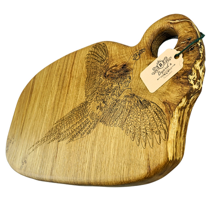 Wooden cutting board with engraved pheasant design and a tag on a white background