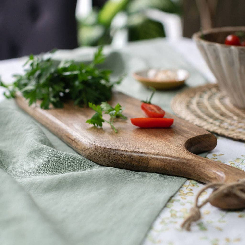 Wooden cutting board with herbs and tomatoes on a tablecloth